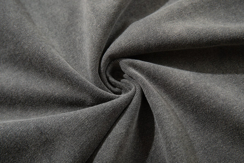 Close-up of washed gray cotton T-shirt fabric with a soft textured weave and spiral fold detail
