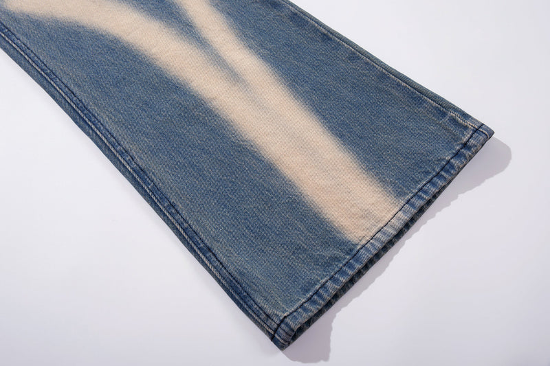 Hem detail of blue denim wide-leg jeans with cream spray-fade pattern