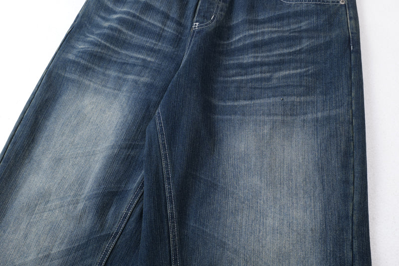 Close-up of dark blue denim leg with faded wash and wide-leg drape