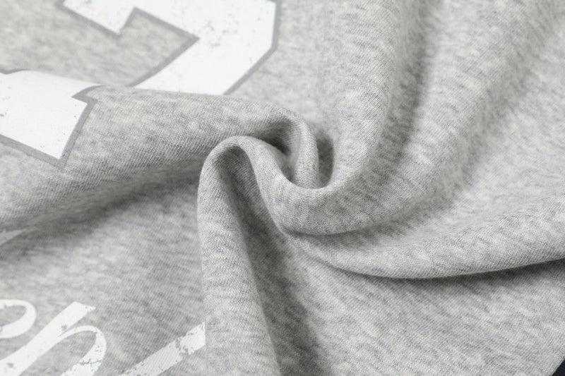 Close-up of gray hoodie fabric with printed number detail and soft folds