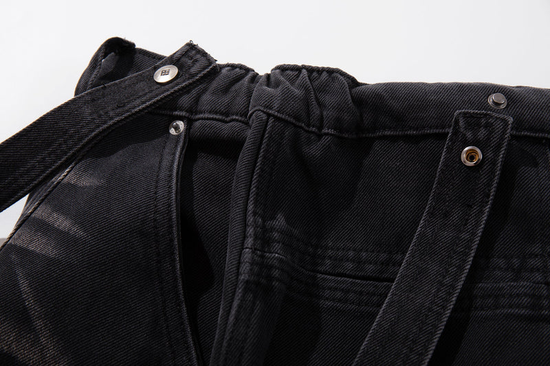 Close-up of waistband, belt loops, snap buttons, and strap detail on dark denim jeans
