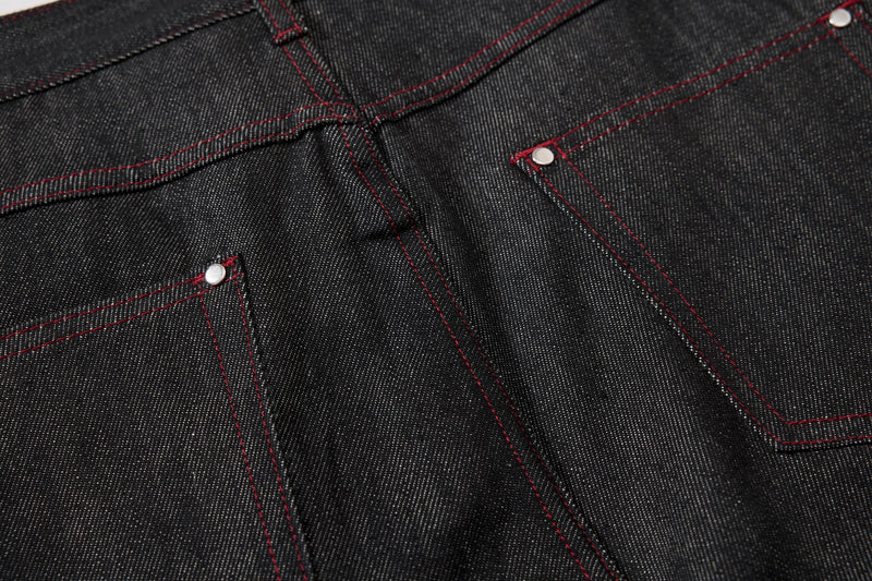 Close-up of black denim yoke and pocket seams with red contrast stitching