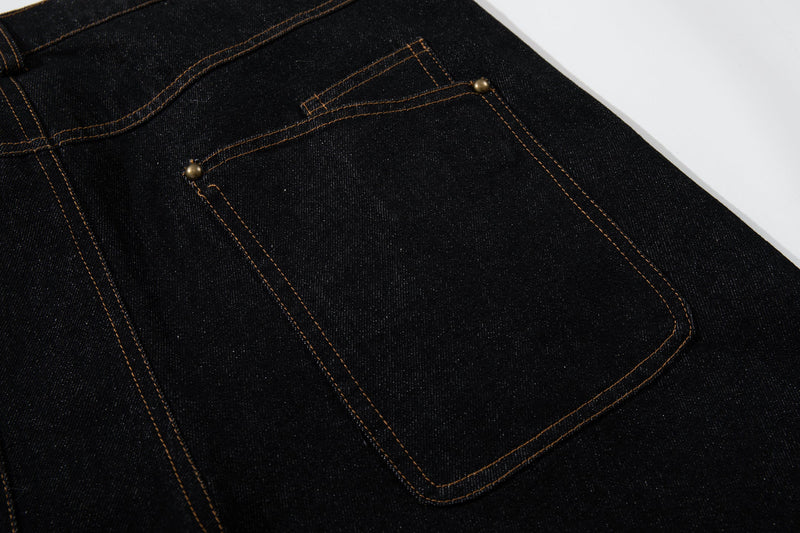 Close-up of the back pocket on black denim pants with curved seam trim