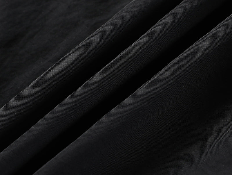 Close-up of black fabric with diagonal draped folds and fine texture