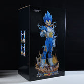 The Seakoff Vegeta collectible figure showcases a blue-haired anime character in battle-worn attire, standing on a rocky base. The 55cm figure has three interchangeable heads (Super Saiyan, Super Saiyan Blue, and Normal) within a box featuring dynamic images on a black background.