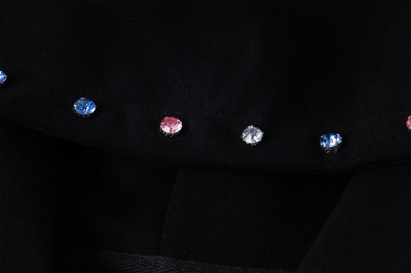 Close-up of black hoodie sleeve cuff with multicolor rhinestone studs