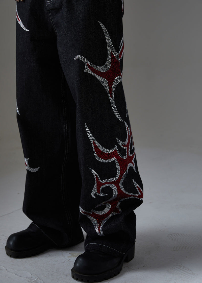 Close-up of black wide-leg denim pants with red and silver rhinestone flames on the lower leg