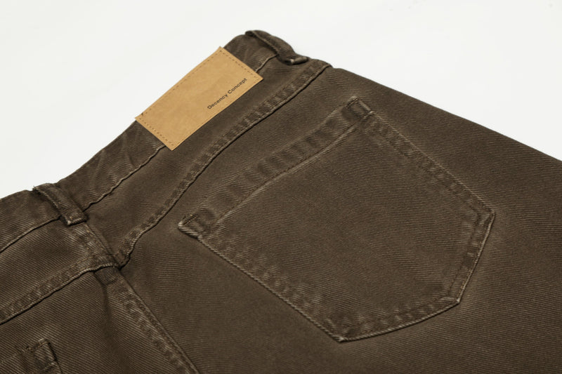 Rear waistband close-up of brown pants with tan brand patch and back pocket detail