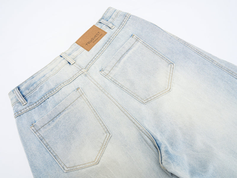Close-up of back waistband and pocket on light wash wide-leg jeans with tan logo patch