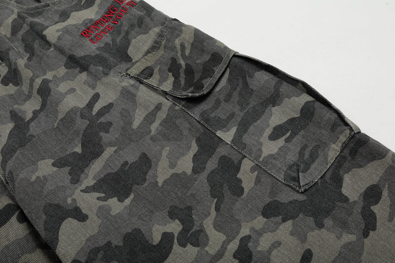 Close-up of camouflage shorts leg pocket with red embroidered text on the upper front