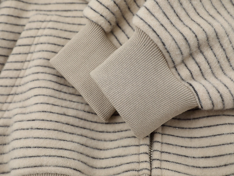 Close-up of beige ribbed cuffs and striped knit sleeve detail