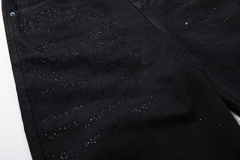 Close-up of the front leg with rhinestone swirl pattern on black denim jeans