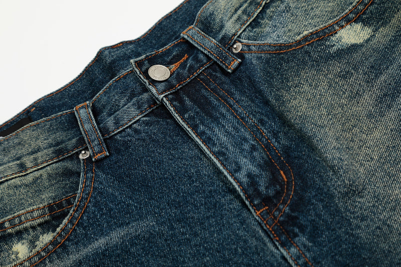 Close-up of the front waistband, button, and belt loops on vintage wash denim