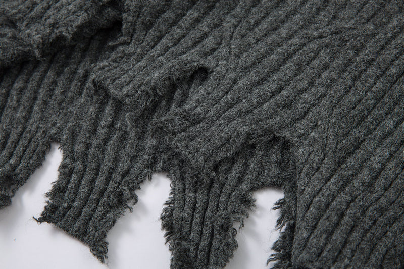 Close-up of charcoal gray ribbed knit with distressed holes and frayed edge