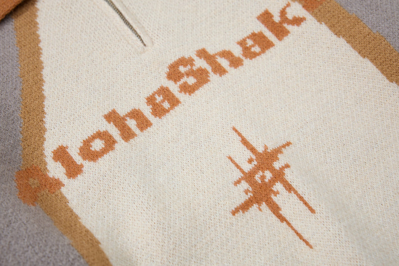 Close-up of AlohaShaka graphic and half-zip front on cream knit sweater