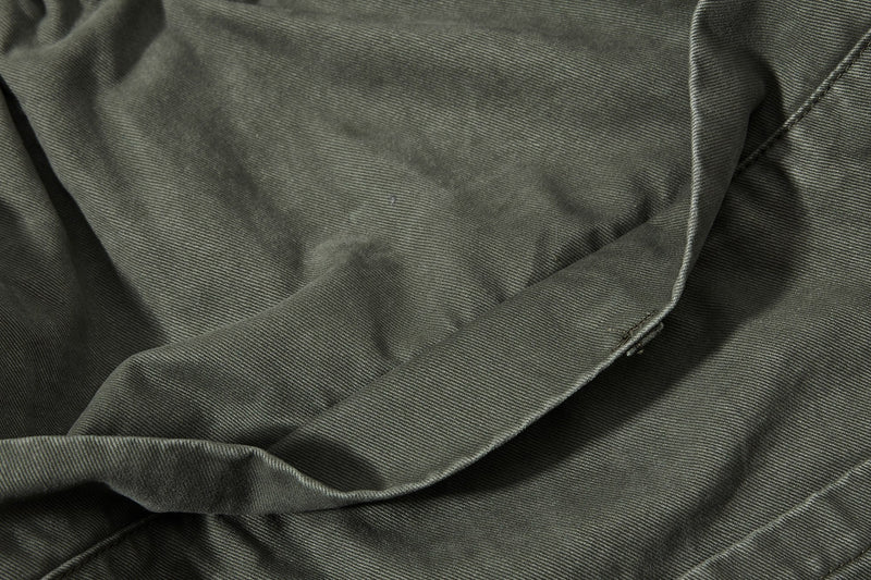 Close-up of olive green pant fabric with soft folds and twill texture