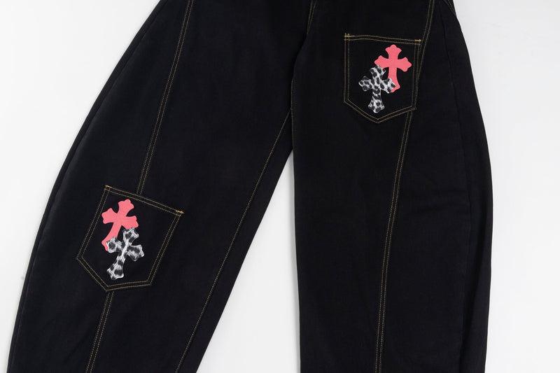 Front legs of black wide-leg jeans with cross patches on one pocket and one thigh pocket