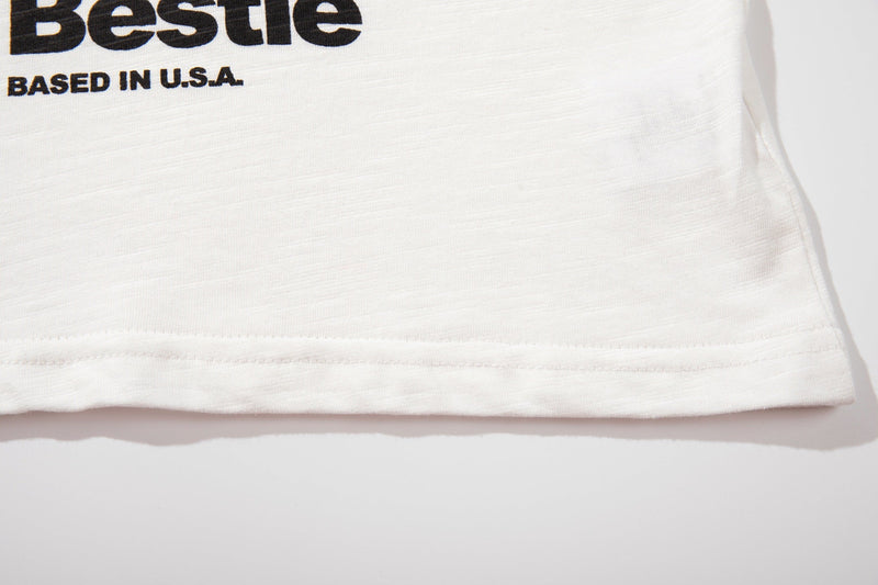 White streetwear ringer tee hem with bold black graphic text and stitched sleeve detail