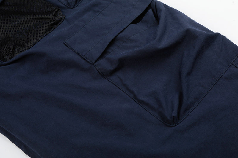 Close-up of navy cargo pants lower pocket flap over black mesh panel