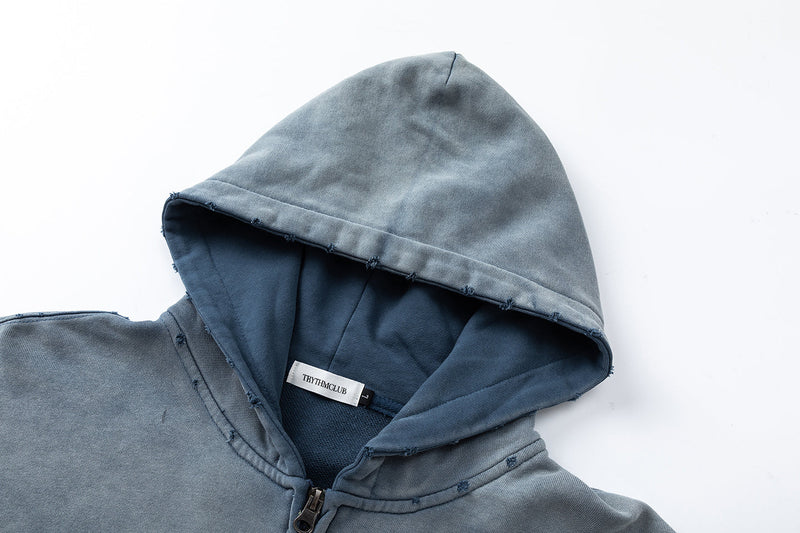Close-up of hood and zipper on washed blue hoodie with raw-edge seam details