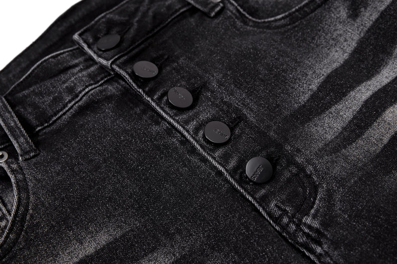 Close-up of black denim front fly with black buttons and seam detailing