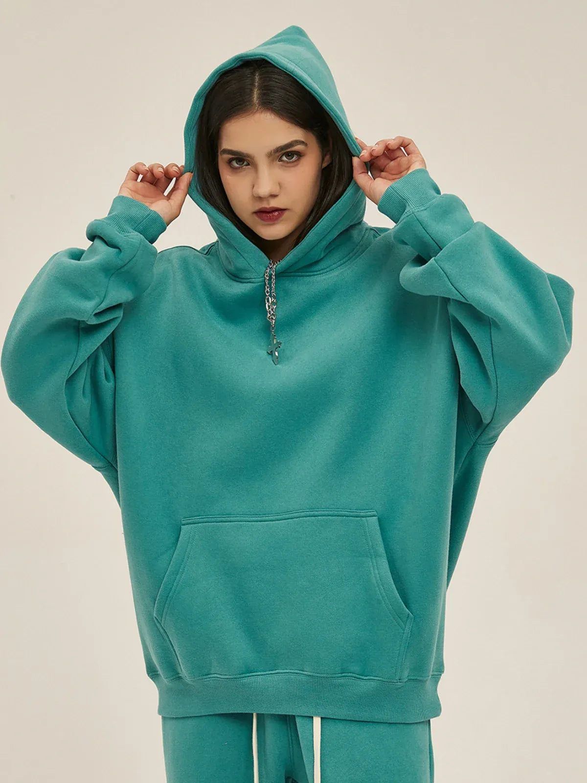 Person wearing a Custom Anime Character Dusty Teal Hoodie - Personalized 350GSM 100% Cotton Pullover with the hood up, holding the strings, standing against a plain background.