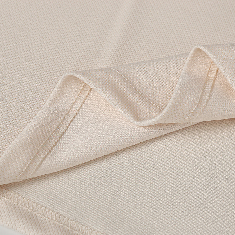Close-up of beige performance jersey fabric with smooth knit texture and stitched hem detailing