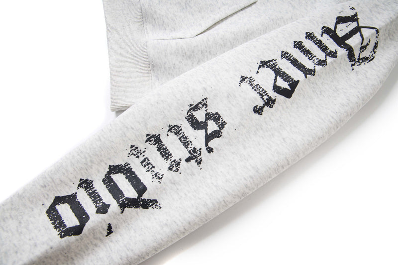Close-up of white hoodie sleeve with distressed black gothic lettering along the forearm