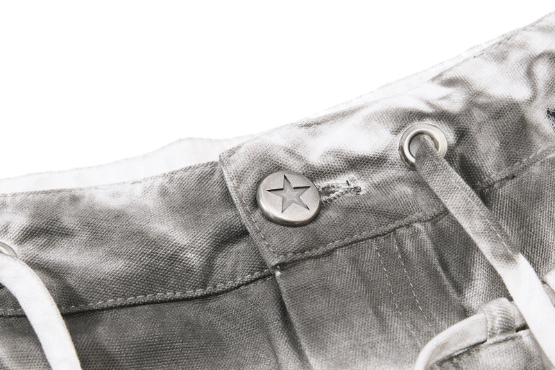 Close-up of waistband button with star engraving and white drawstring on gray denim