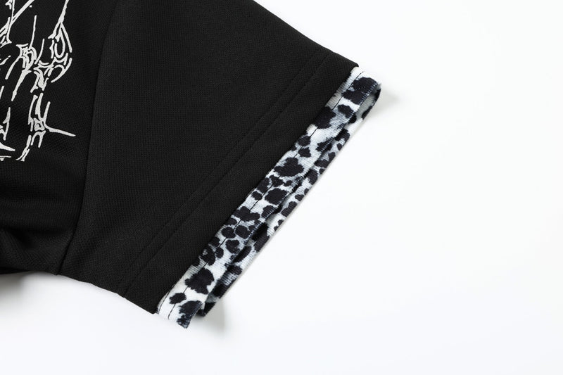 Black polo shirt sleeve with white gothic cross graphic and leopard print trim on cuff