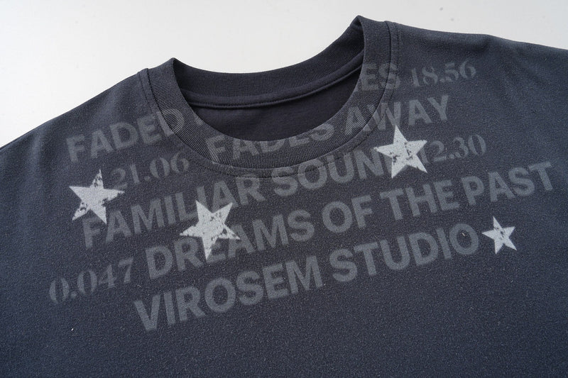 Dark navy graphic T-shirt with faded slogan print and scattered star graphics, featuring a ribbed crew neckline