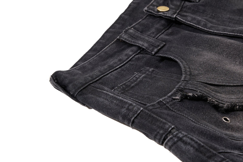 Close-up of black denim front pocket opening with frayed seams and a metal eyelet