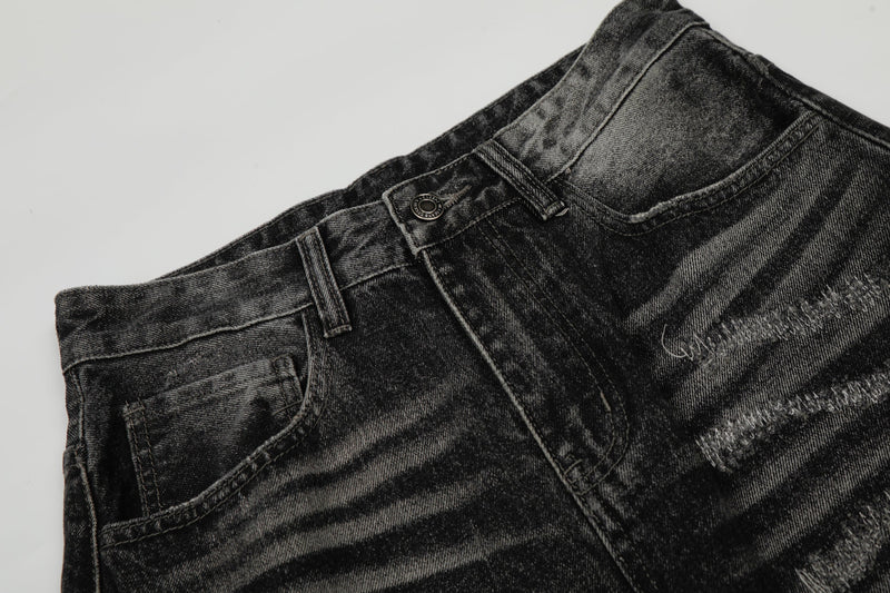 Close-up of front waistband, button, belt loops, and faded black denim texture