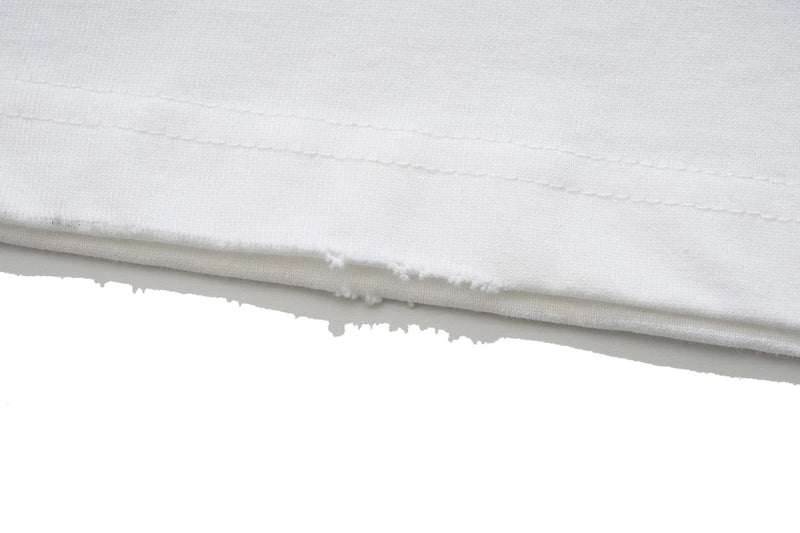 Close-up of a white graphic T-shirt hem with stitched seams and raw distressed edge detail