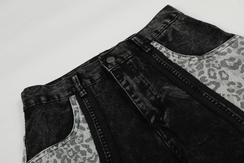 Close-up of black denim waistband with button and leopard panel seam