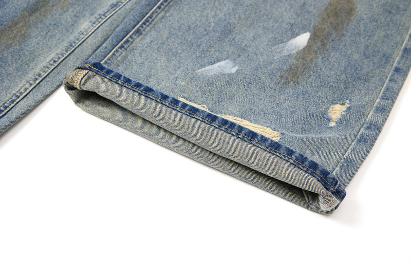 Close-up of rolled hem and distressed lower leg on washed blue jeans