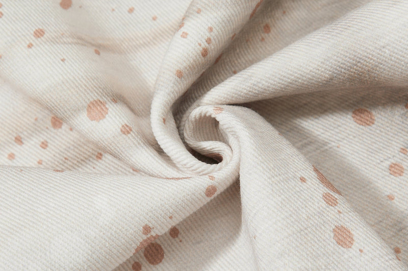 Close-up of gathered cream denim fabric with brown splatter print
