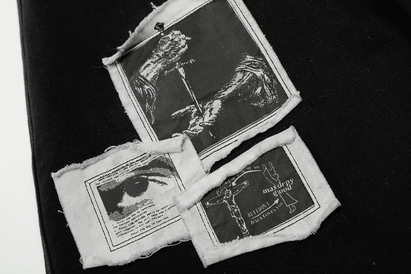 Close-up of graphic fabric patches on black pants with frayed white edges