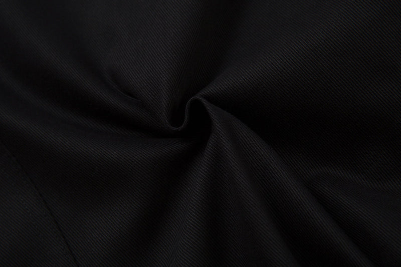 Close-up of black twill fabric with a soft fold and diagonal weave texture