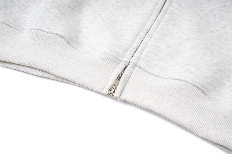 Close-up of white hoodie ribbed hem and bottom zipper detail