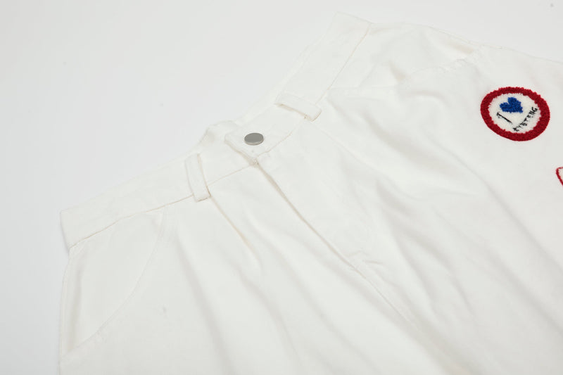 Close-up of white cargo shorts waistband and circular heart patch