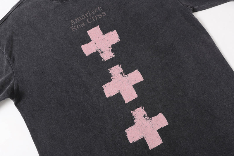 Angled front view of a black oversized long sleeve tee with pink cross graphics