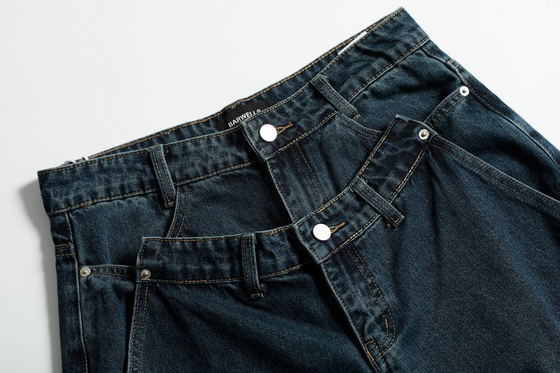 Close-up of the front waistband on dark wash jeans with double buttons, belt loops, and stitching