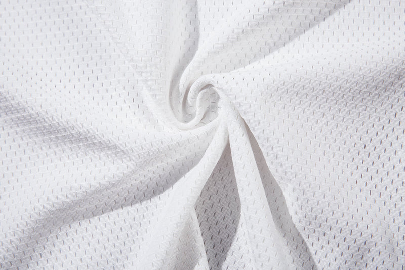 Close-up of white textured mesh jersey fabric with subtle perforations and gathered folds