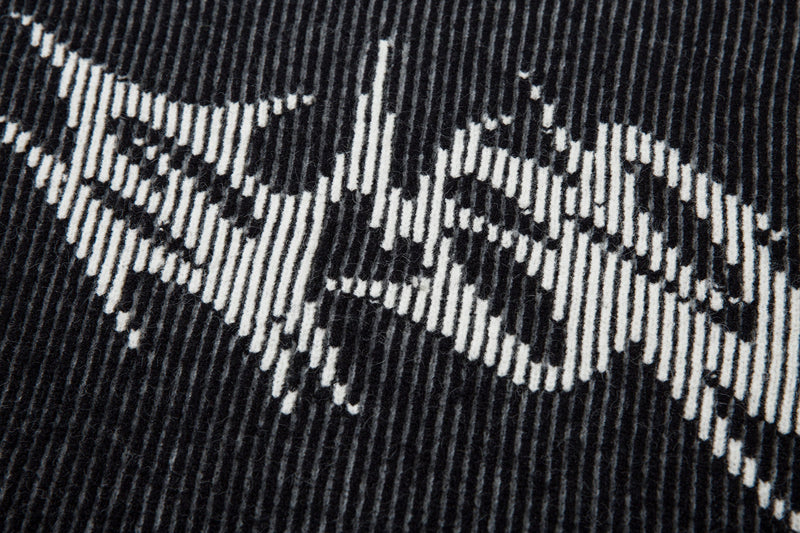 Close-up of white lightning graphic on black ribbed knit sweater