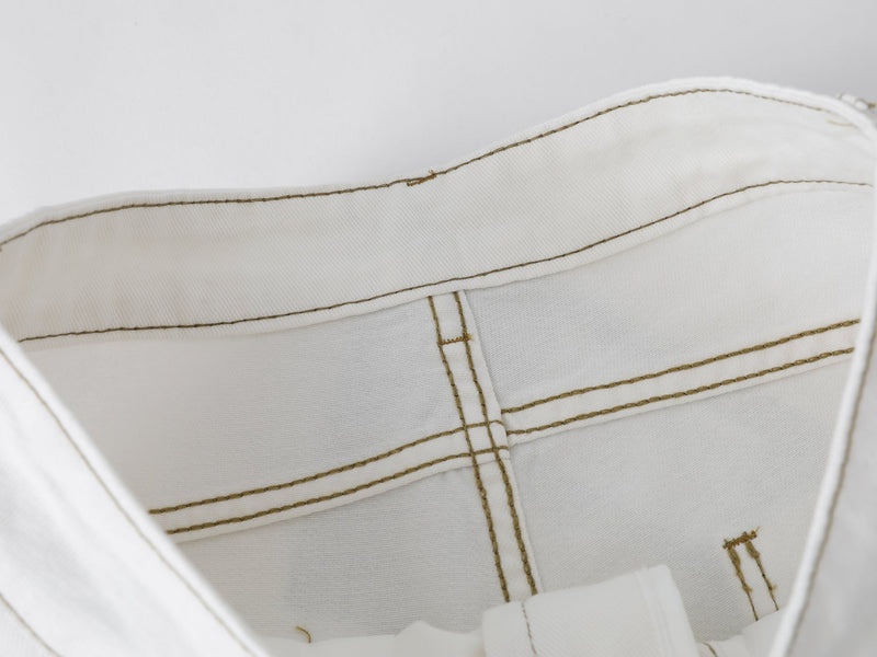 Close-up inside the waistband of white denim shorts showing stitching and splatter detail
