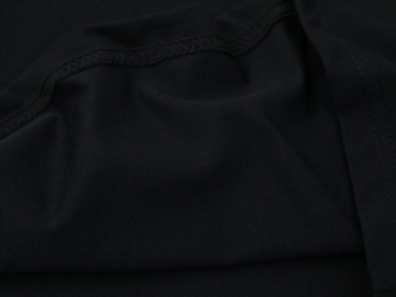 Close-up of black fabric hem with visible stitching and ribbed seam detail