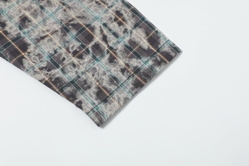 Close-up of plaid sleeve hem with faded gray, teal, and brown check pattern