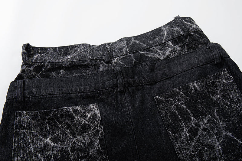 Top back view of black denim waistband and cracked panel detail across the yoke