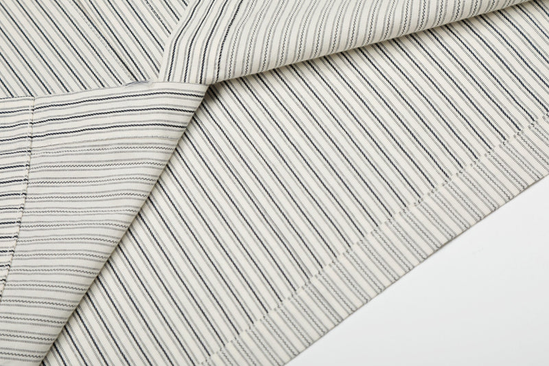 Cream pinstripe button-up shirt fabric with black stitched stripes and subtle patch graphic detailing